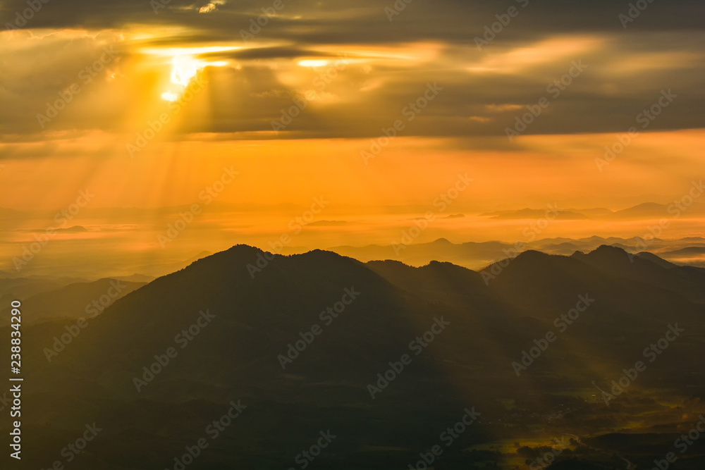 landscape sunrise on hill mountain with rays of sunlight shining on the cloud yellow sky