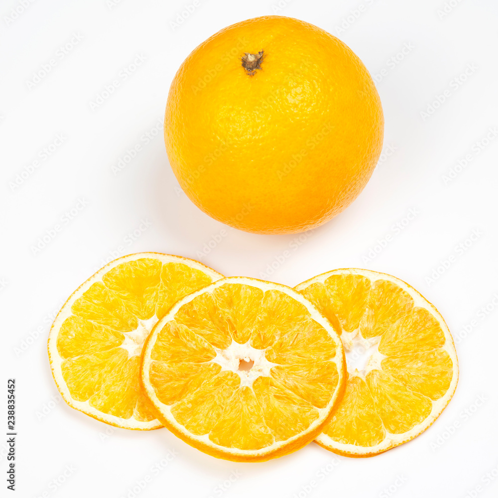 Dried orange slices next to fresh orange on a white background Dried orange slices next to fresh orange on a white background