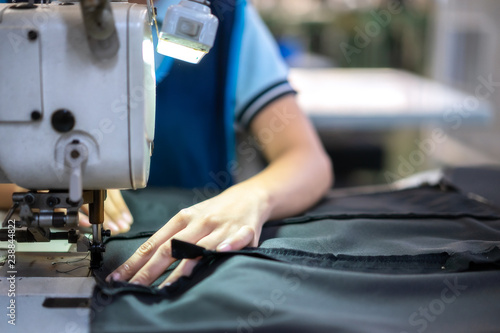 Hands of young girl using sewing machine in workshop.