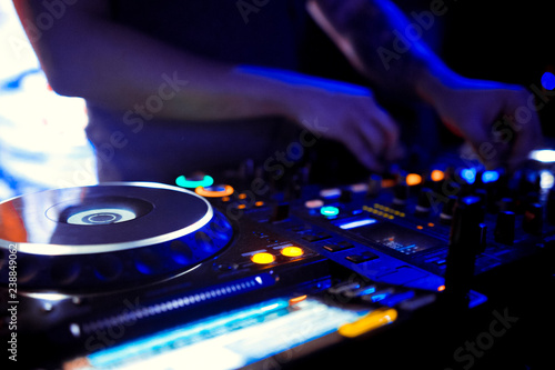 DJ console cd mp4 deejay mixing desk Ibiza house music party in nightclub with colored disco lights.