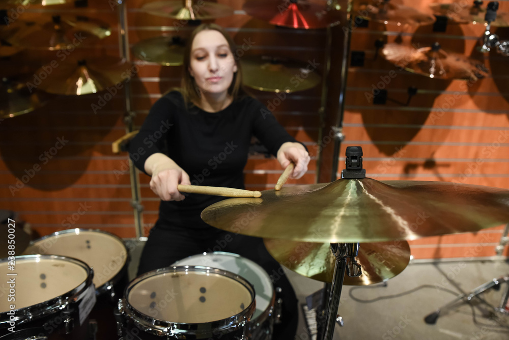 Obraz premium Professional drum set closeup. Beautiful young woman drummer with drumsticks playing drums and cymbals, on the live music rock concert or in recording studio 