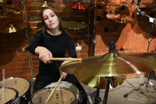 Professional drum set closeup. Beautiful young woman drummer with drumsticks playing drums and cymbals, on the live music rock concert or in recording studio 