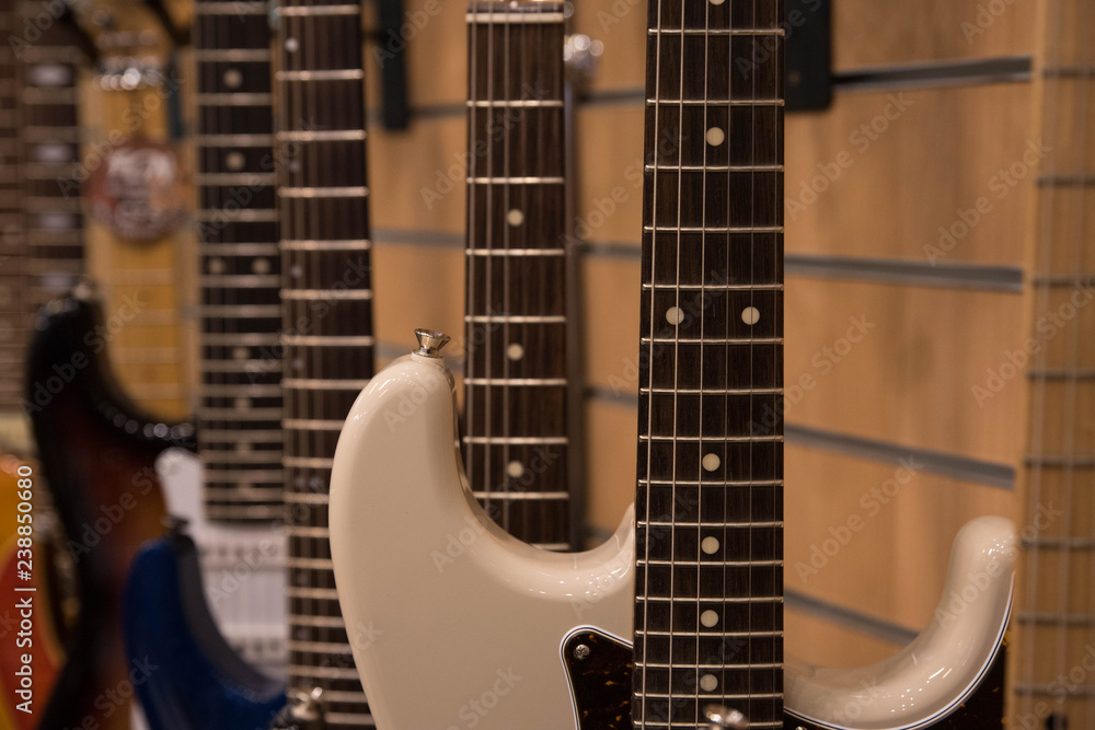 Fototapeta premium Closeup of row of different colorful guitars on the display for sale hanging in a music shop 