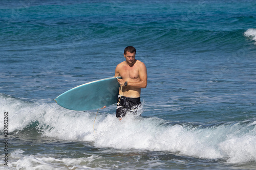 Photography young man comes out of the ocean with a board after surfing