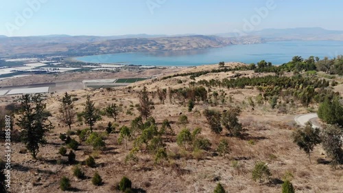 Aerial Farward Mountains, trees And Hills With Big Blue Lake In The Background At Day In Clear Skies photo
