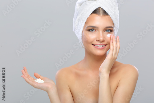 Skin care woman putting face cream. Facial beauty closeup of beautiful Caucasian female model isolated on white background.