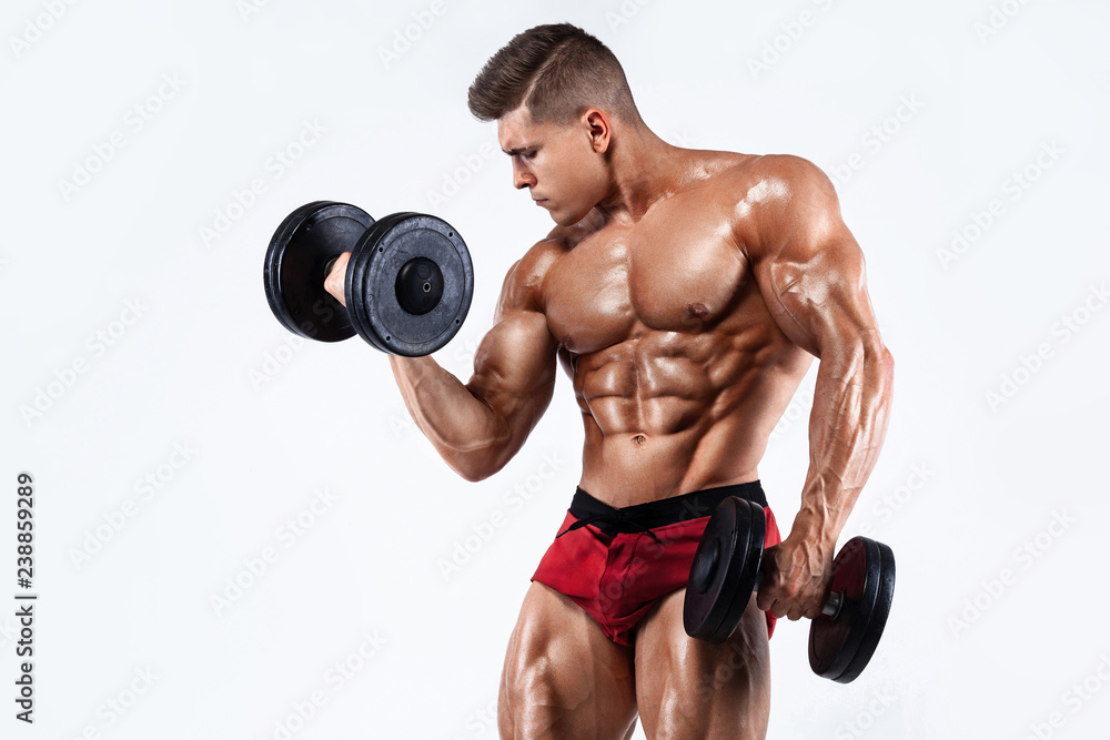 Brutal strong muscular bodybuilder athletic man pumping up muscles with dumbbell on white background. Workout bodybuilding concept. Copy space for sport nutrition ads.
