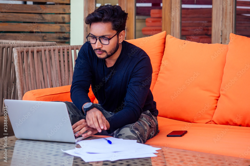Indian young business people businessman freelancer working outdoors chaise lounge on the beach with laptop.two successful friends freelancing surfing remote work summer vacation in tropical paradise. Indian young business people businessman freelancer working outdoors chaise lounge on the beach with laptop.two successful friends freelancing surfing remote work summer vacation in tropical paradise.