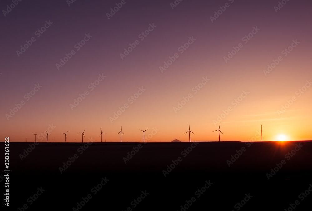 Wind power stations producing renewable engergy in a beautiful sunset