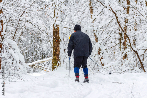 Elderly man skis in the snow-covered forest. Healthy lifestyle