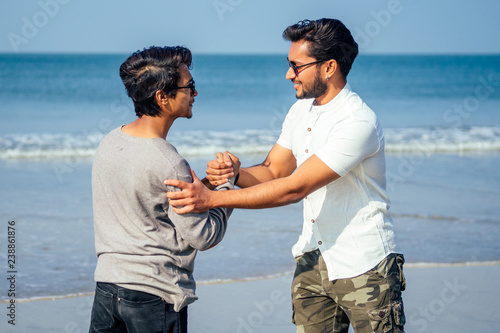 Happy holi two indian stylish mans young friends hugging on the beach by the sea.long-awaited meeting diwali of the brothers in India Goa tropical paradise summer vacation blue sky and ocean