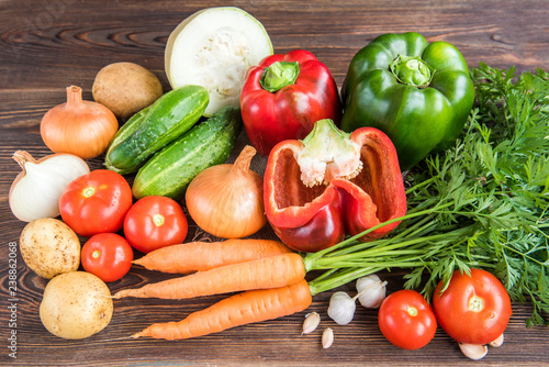 Vegetables on wooden background. Carrot, red pepper, cucumbers, tomatoes, garlic, potatoes and onions.