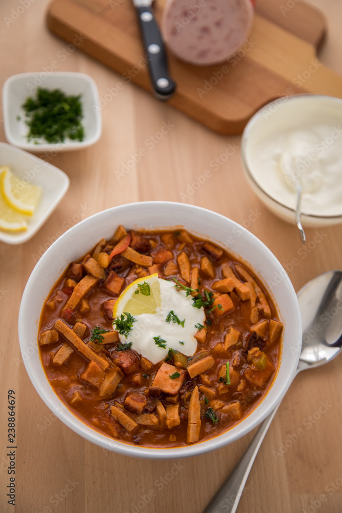 Typische DDR Soljanka Suppe in Schale mit Schmand und Zitrone Typische DDR Soljanka Suppe in Schale mit Schmand und Zitrone