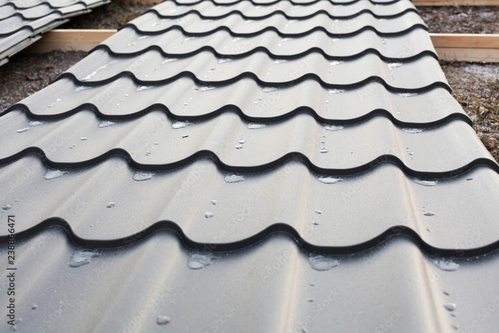 Close up photo of new black sheet wavy roof pattern lying on the ground ready to be installed on the top of new house