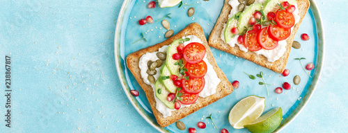 Toasts with feta cheese, tomatoes, avocado, pomegranate, pumpkin seeds and lenseed sprouts. Diet breakfast. Delicious and healthy food. Flat lay. Top view. Banner