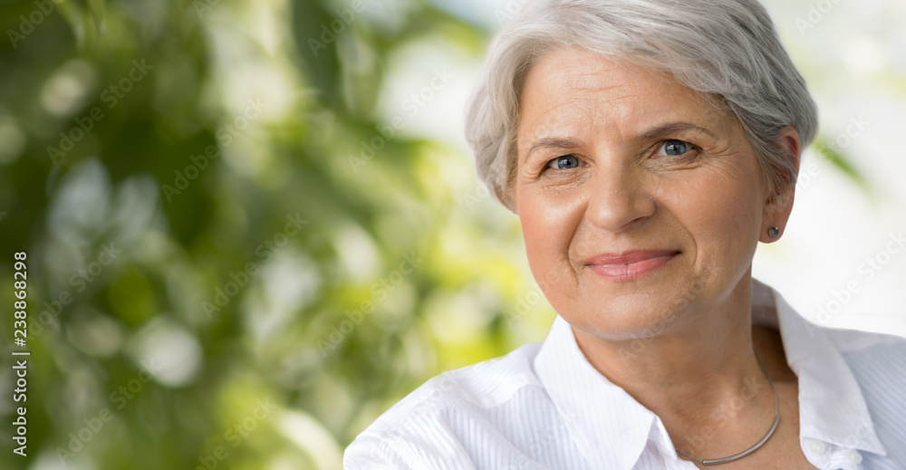old age and people concept - portrait of smiling senior woman over green natural background old age and people concept - portrait of smiling senior woman over green natural background