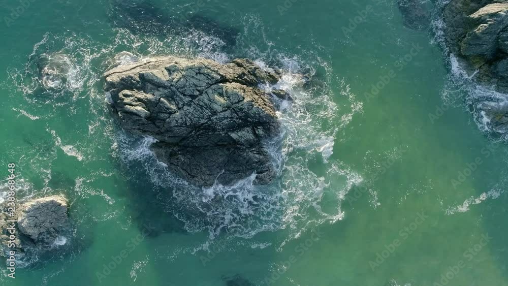 Zooming aerial view of pristine clear ocean with a sand bottom & waves