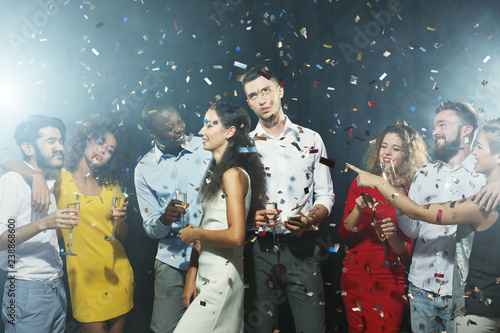 Multiracial friends having fun under confetti at party