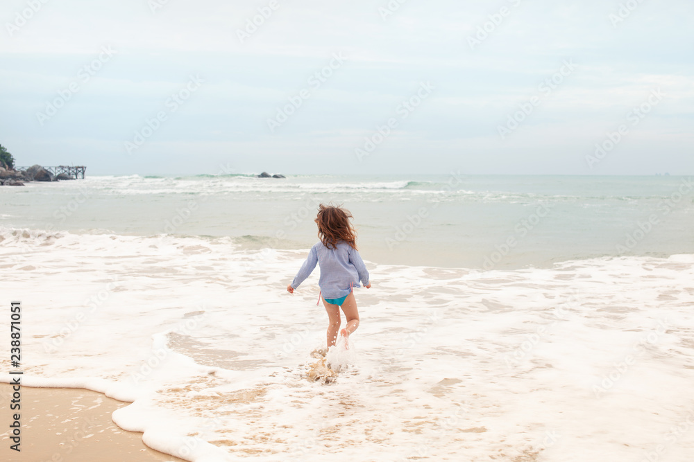 Five-year-old girl playing on the sandy beach of the sea