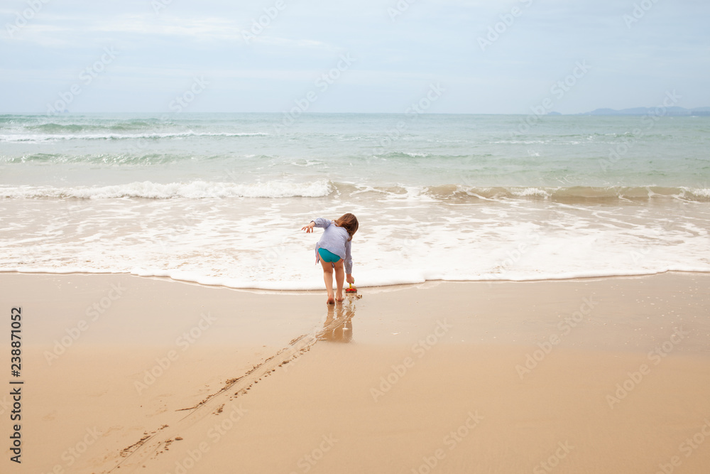 Five-year-old girl playing on the sandy beach of the sea