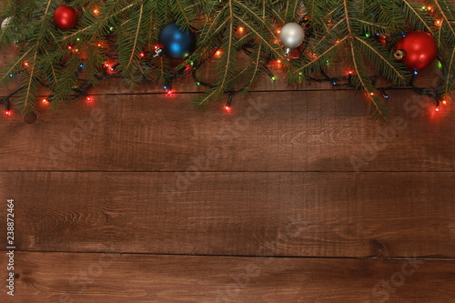 Fir tree branches, baubles and fairy lights. Christmas background concept. Border and copy space on wooden boards.