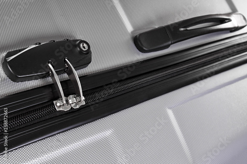 Closeup photo of gray traveler suitcase with combination lock and zipper