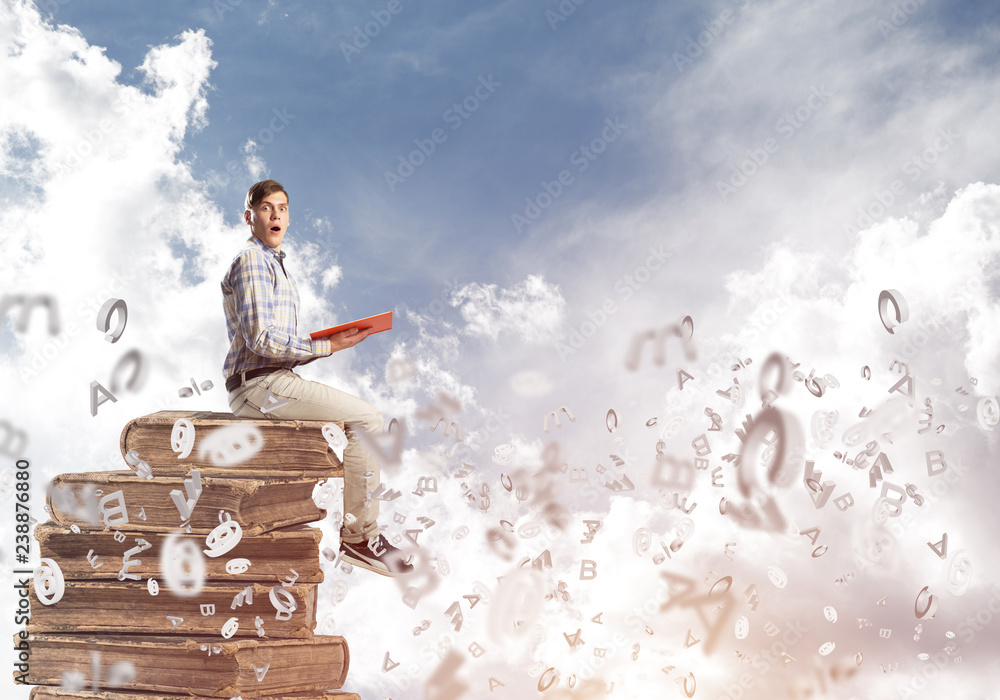 Man student on stack reading book and symbols flying around Man student on stack reading book and symbols flying around