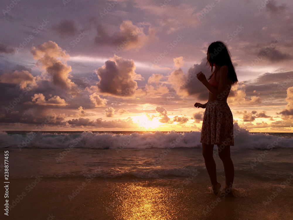 Silhouette of beautiful woman on the colorful ocean sunset background
