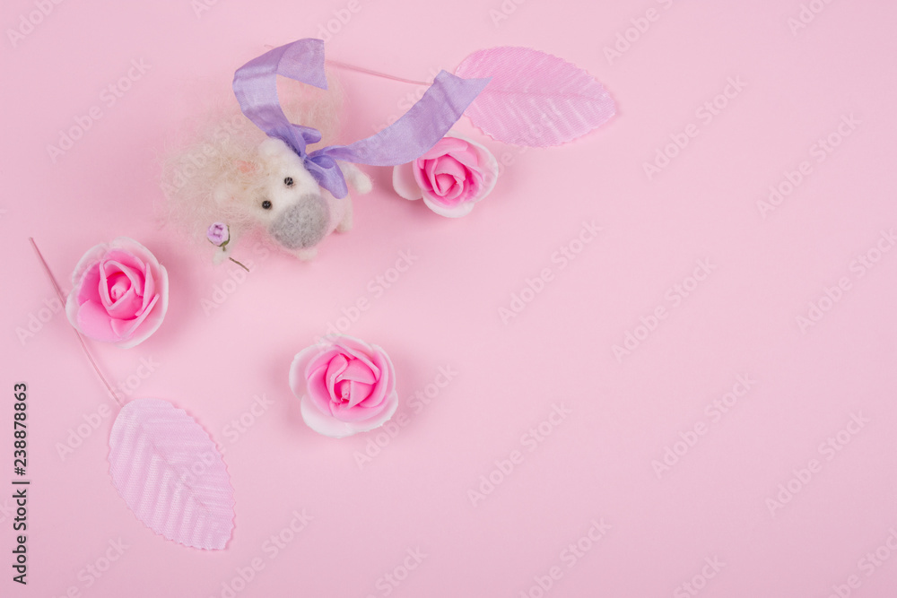 Tiny unicorn toy made of wool, handmade rose buds and handmade pink leaves on a pastel pink background (minimal concept, top view), copy space