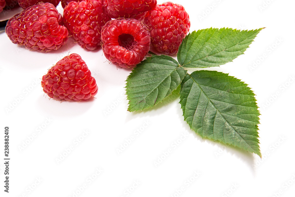 White cup with ripe raspberries and green leaf isolated on white background. White cup with ripe raspberries and green leaf isolated on white background.