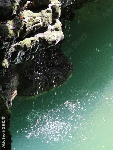 water drops fall from a stone cliff into a river