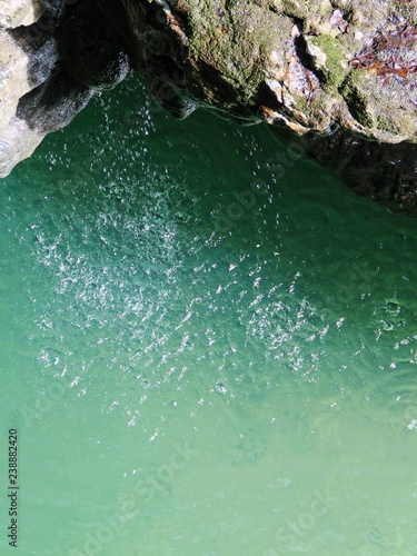 water drops fall from a stone cliff into a river