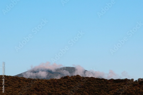 against the blue sky is visible a mountain shrouded in clouds