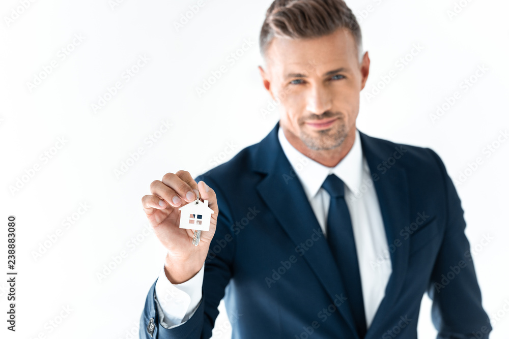 selective focus of handsome businessman holding key from house and looking at camera isolated on white selective focus of handsome businessman holding key from house and looking at camera isolated on white