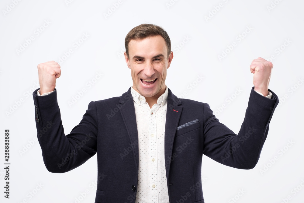 Φωτογραφία Pleased and happy young italian man is smiling broadly and showi