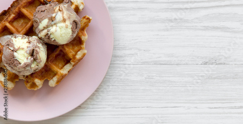 Traditional belgian waffle with icecream on pink plate over white wooden surface, top view. Copy space. © Liudmyla