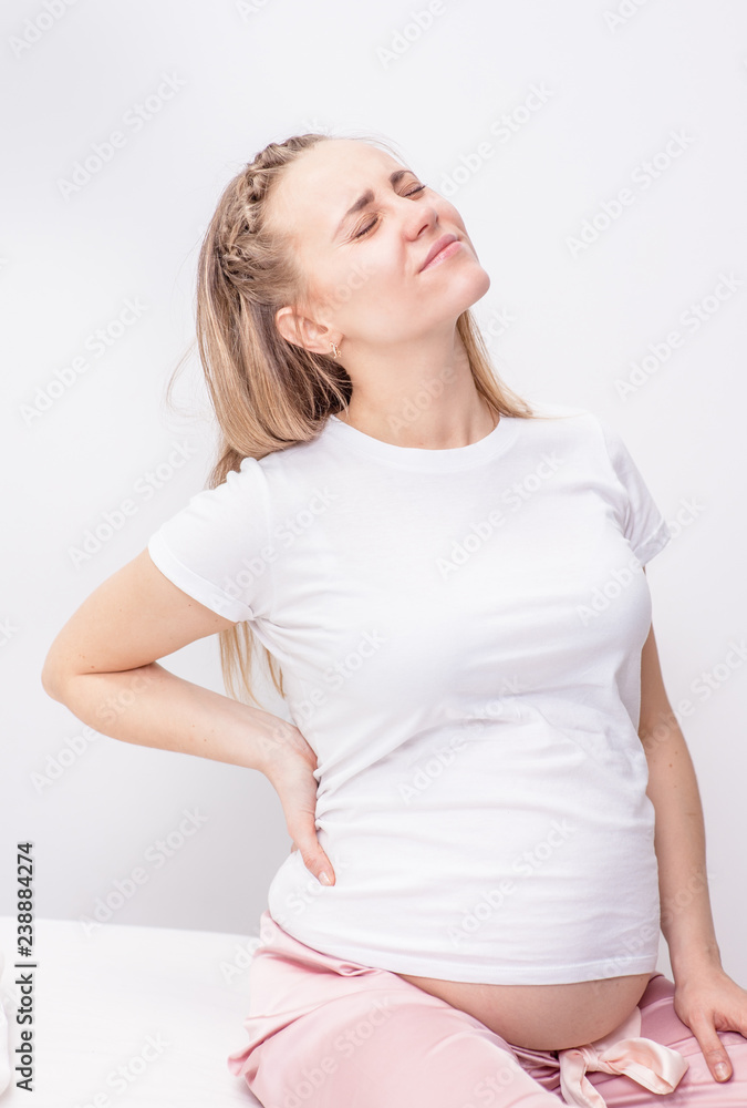 Young pregnant woman suffering from backache at home Young pregnant woman suffering from backache at home