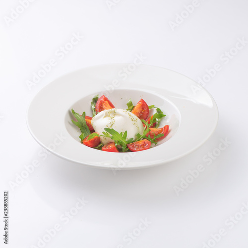 Salad with mozzarella on a white plate. Isolated.