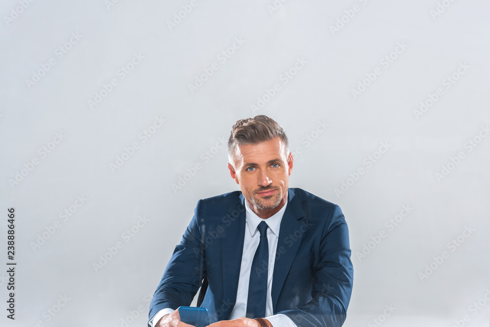 handsome businessman holding smartphone and looking away isolated on white handsome businessman holding smartphone and looking away isolated on white