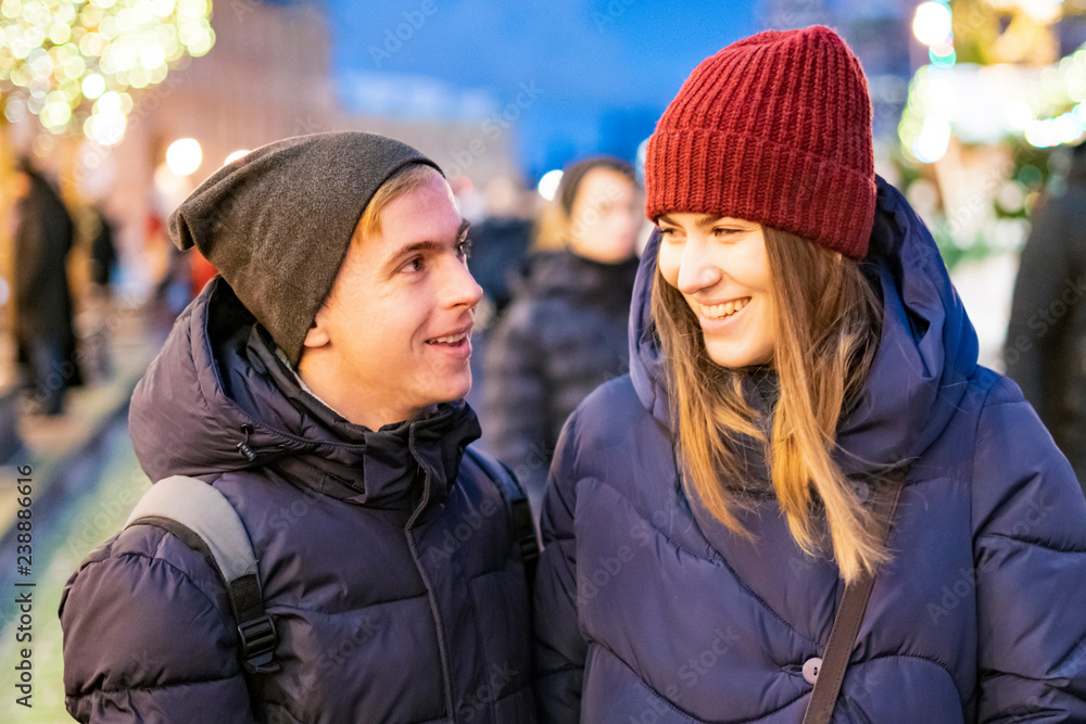 young couple walk in the night city, a lot of street lights, talking smiling and having fun f young couple walk in the night city, a lot of street lights, talking smiling and having fun f