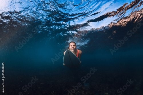 Attractive surfer woman with surfboard dive underwater with under wave. Duck dive in ocean
