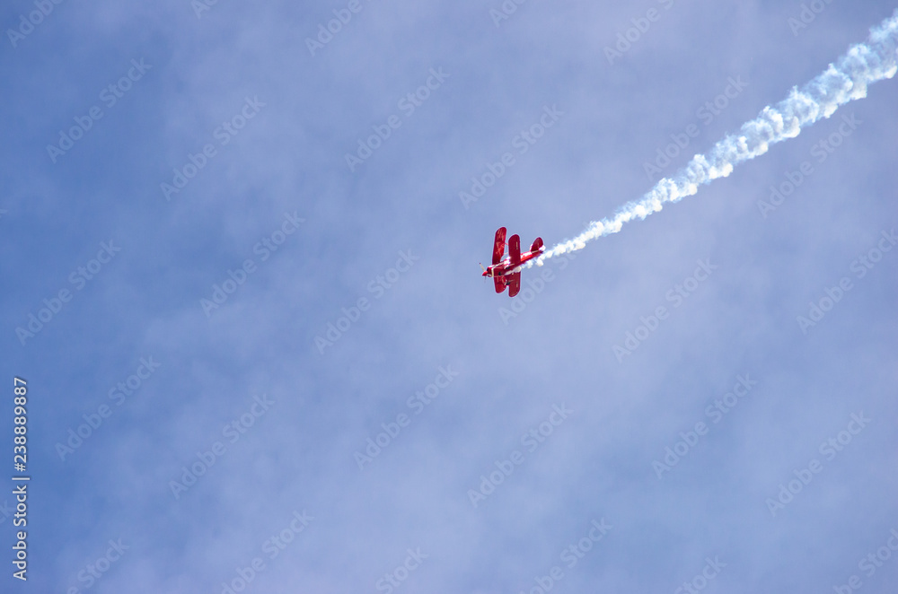 red airplane doing acrobatics in blue sky