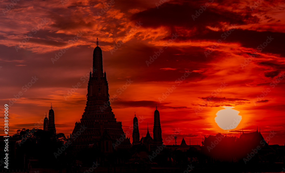 Wat Arun Ratchawararam at sunset with beautiful red and orange sky and clouds. Wat Arun buddhist temple is the landmark in Bangkok, Thailand. Attraction art. Silhouette dramatic sky and temple.