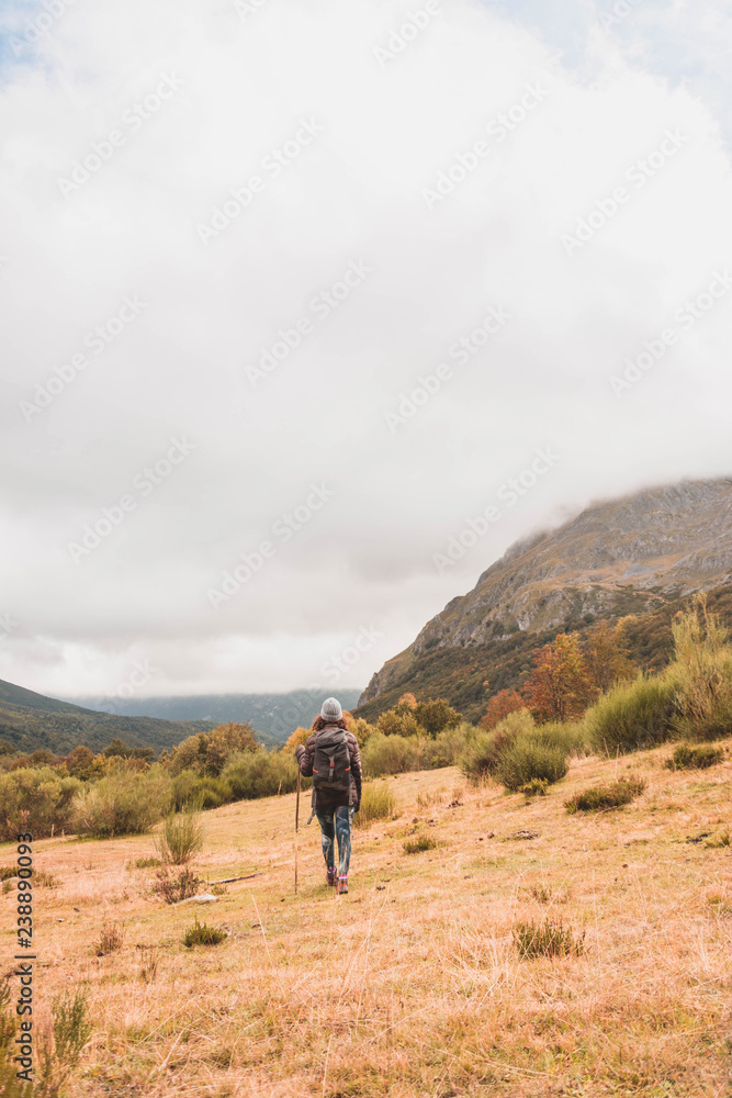 Woman with backpack and cane walking near peak of mountain Woman with backpack and cane walking near peak of mountain