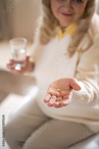 Senior woman holding pills and a glass of water