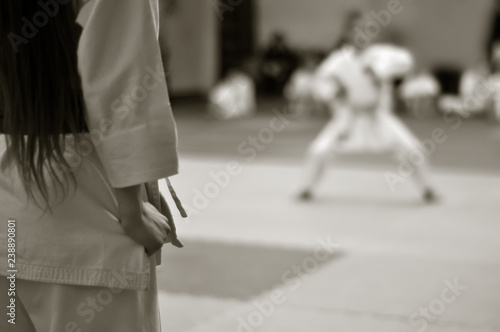 Karate exam. The girl is preparing for performance. Black and white photo without faces with space for text.