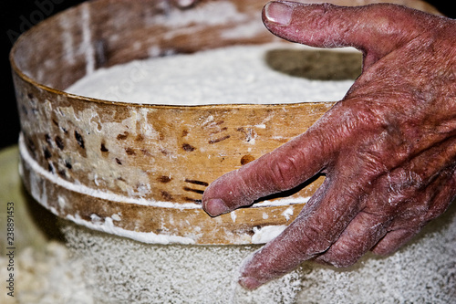 Grandma's old wrinkled hands sift flour © Pavlo