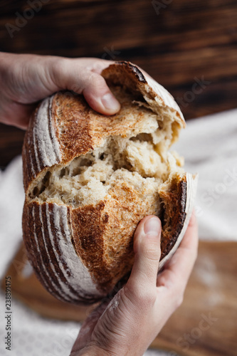 man breaks hands a loaf of fresh bread