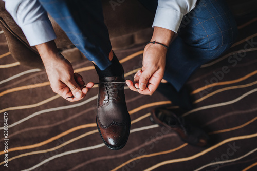 Groom s shoes. Tying shoelaces. Wedding interior. Fees groom in the room. Wedding concept. Wedding photography.