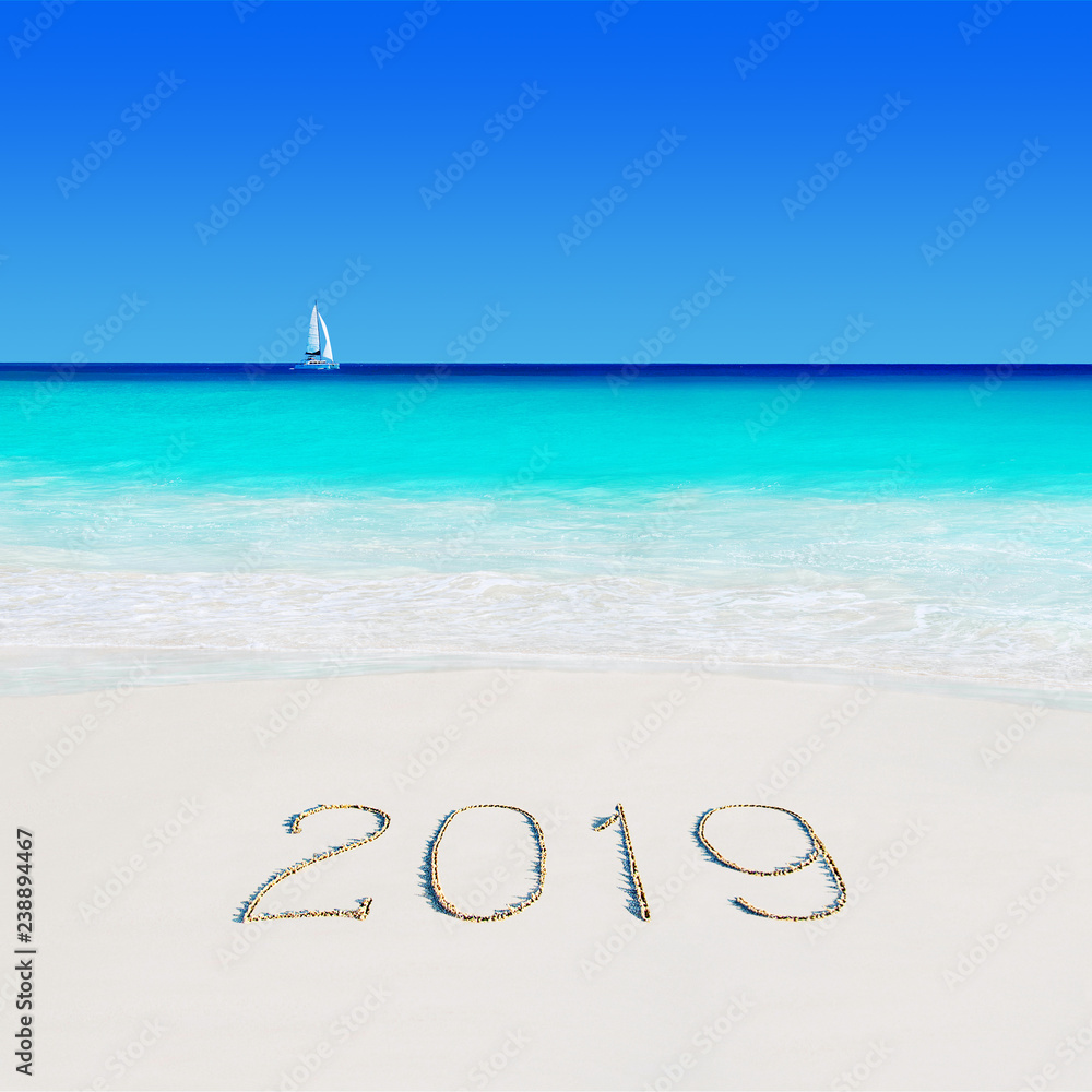 Yacht under sail at idyllic beach and season of 2019 year caption on sand